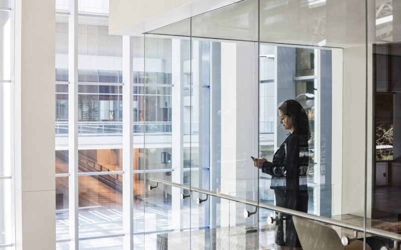 Businesswoman standing in a conference room window in a large business center.