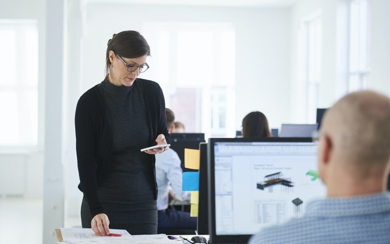 Colleagues in office using mobile phone and computer