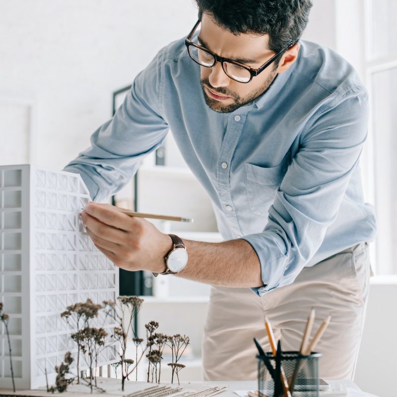handsome architect working with architecture model on table in office