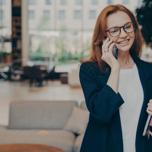 Portrait of attractive positive european business woman having mobile conversation