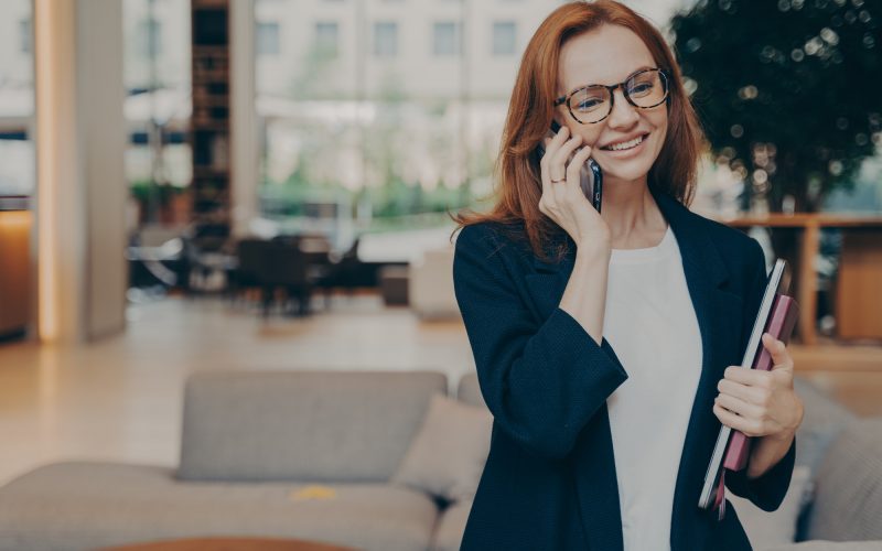 Portrait of attractive positive european business woman having mobile conversation