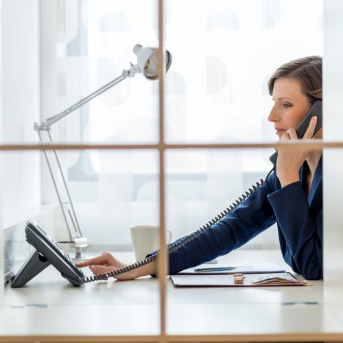 Young businesswoman or secretary dialing a phone number
