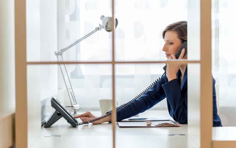 Young businesswoman or secretary dialing a phone number